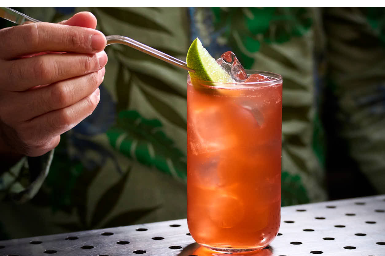 Bartender miscela un cocktail al bancone con mixing glass e bottiglie