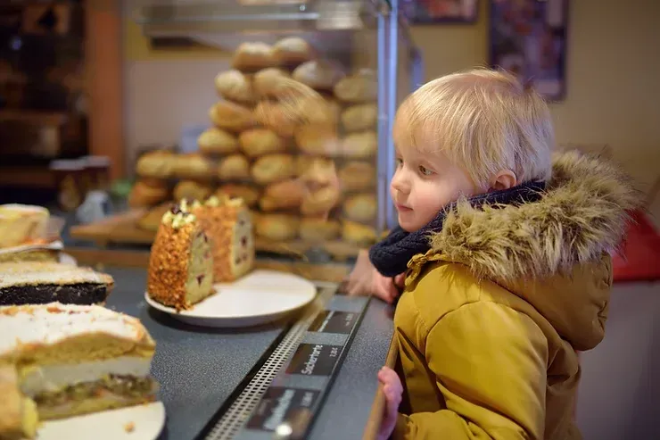 A young boy is looking at sweets in a bakery.