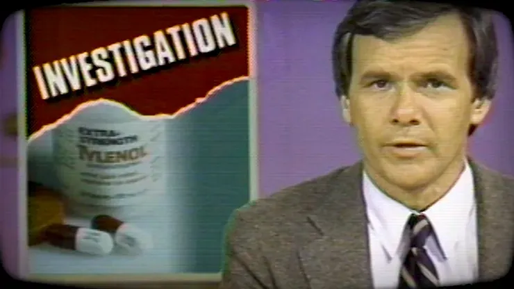 A man in a suit stands in front of a poster