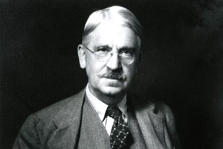A man wearing glasses and a mustache in a suit and tie