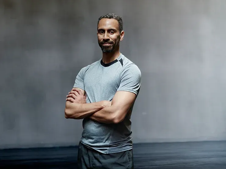 Un uomo è in piedi con le braccia incrociate in una palestra.