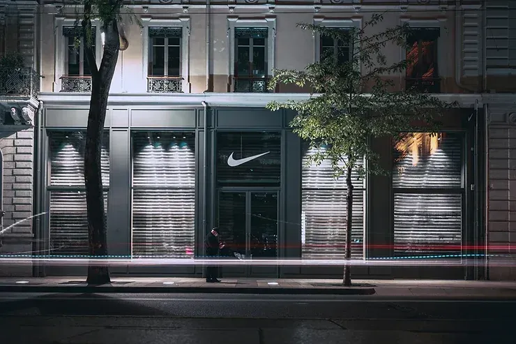 A man walks past a Nike store at night.
