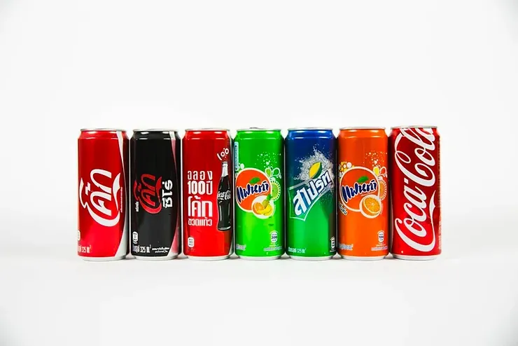 A row of Coca-Cola, Fanta, Sprite, and Dr. Pepper cans lined up.