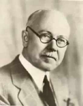A black and white photo of Claude Hopkins, wearing glasses and a suit and tie